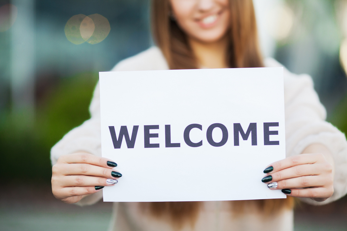 Young Woman Holding Welcome Sign 
